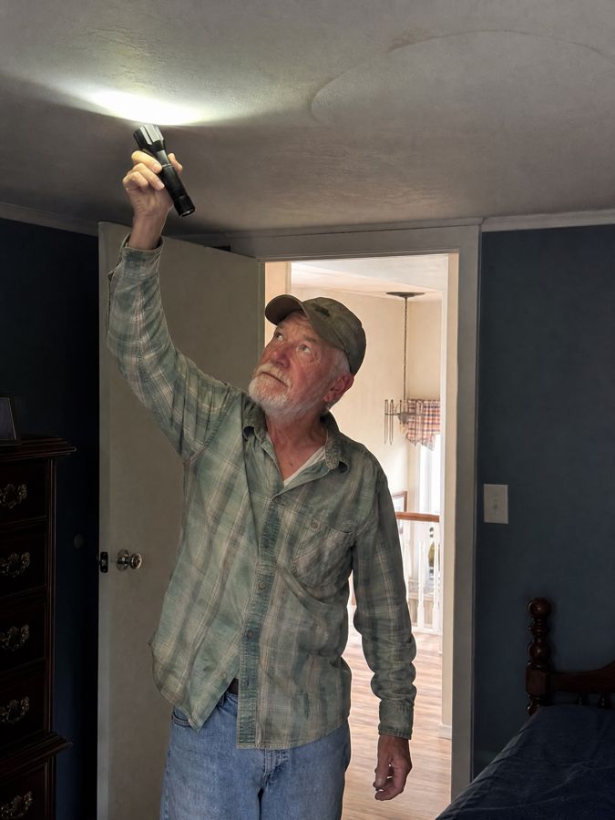 Earl LeBlanc checking a ceiling with a flashlight